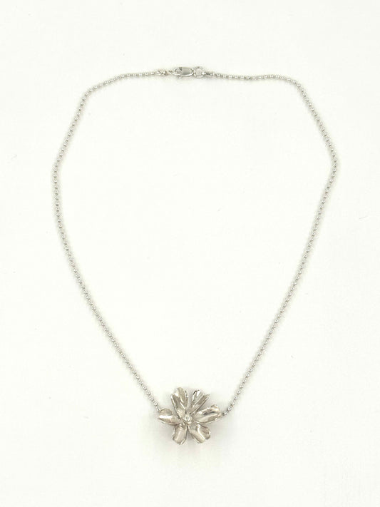 A silver chain necklace with a textured, flower-like metallic pendant, displayed against a plain white background.
