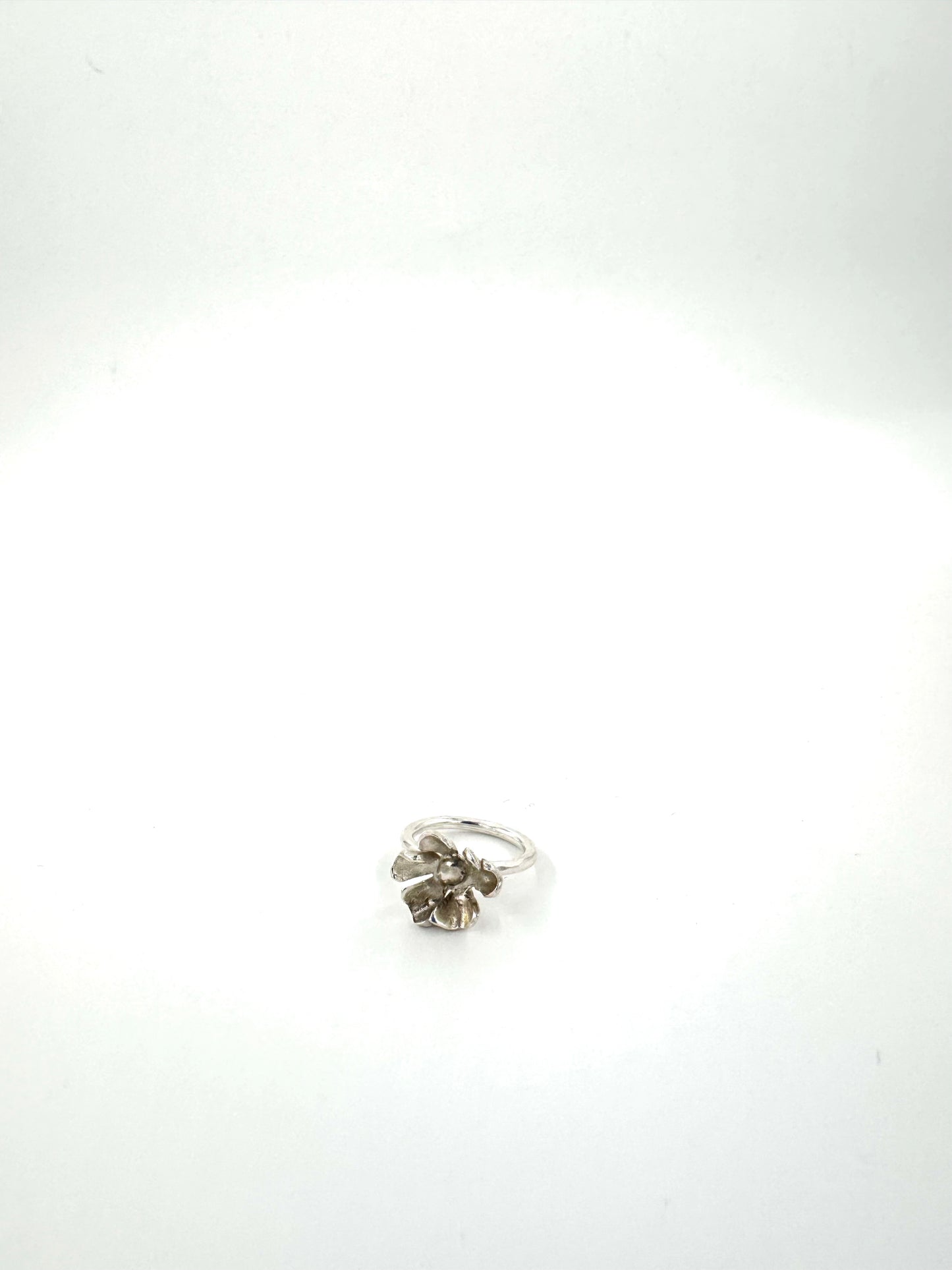 A silver ring with a textured, organic flower-like cluster setting, photographed on a plain white background.