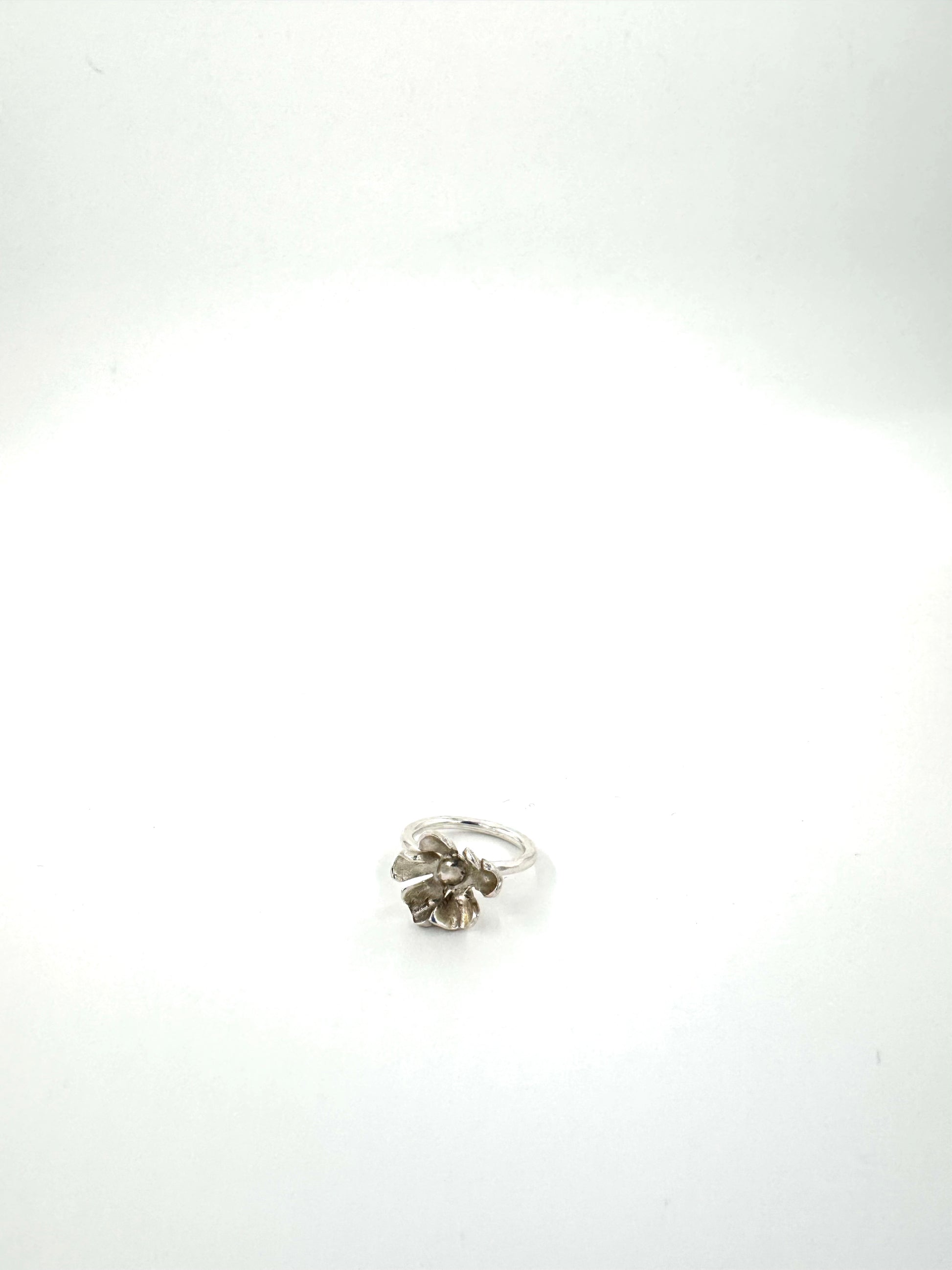 A silver ring with a textured, organic flower-like cluster setting, photographed on a plain white background.