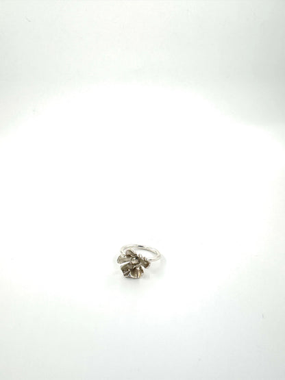 A silver ring with a textured, organic flower-like cluster setting, photographed on a plain white background.