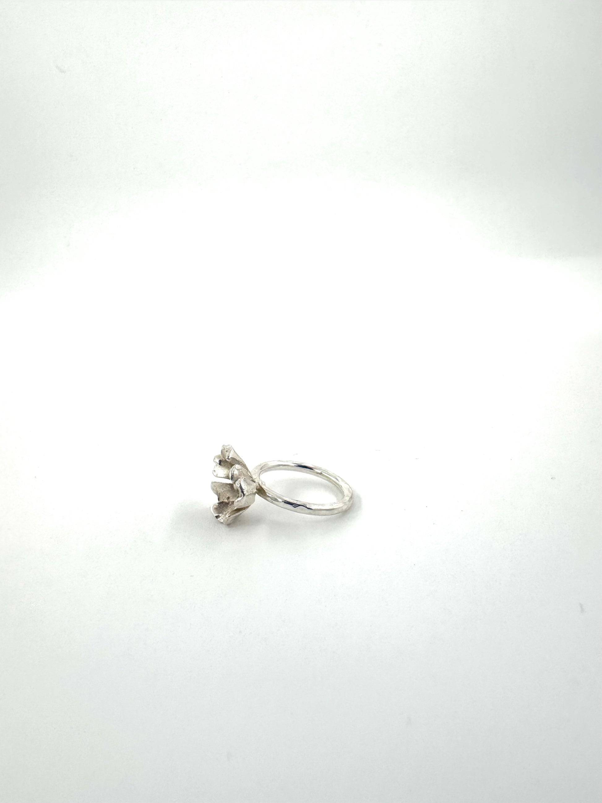 A silver ring with a small floral cluster setting, photographed on a plain white background.